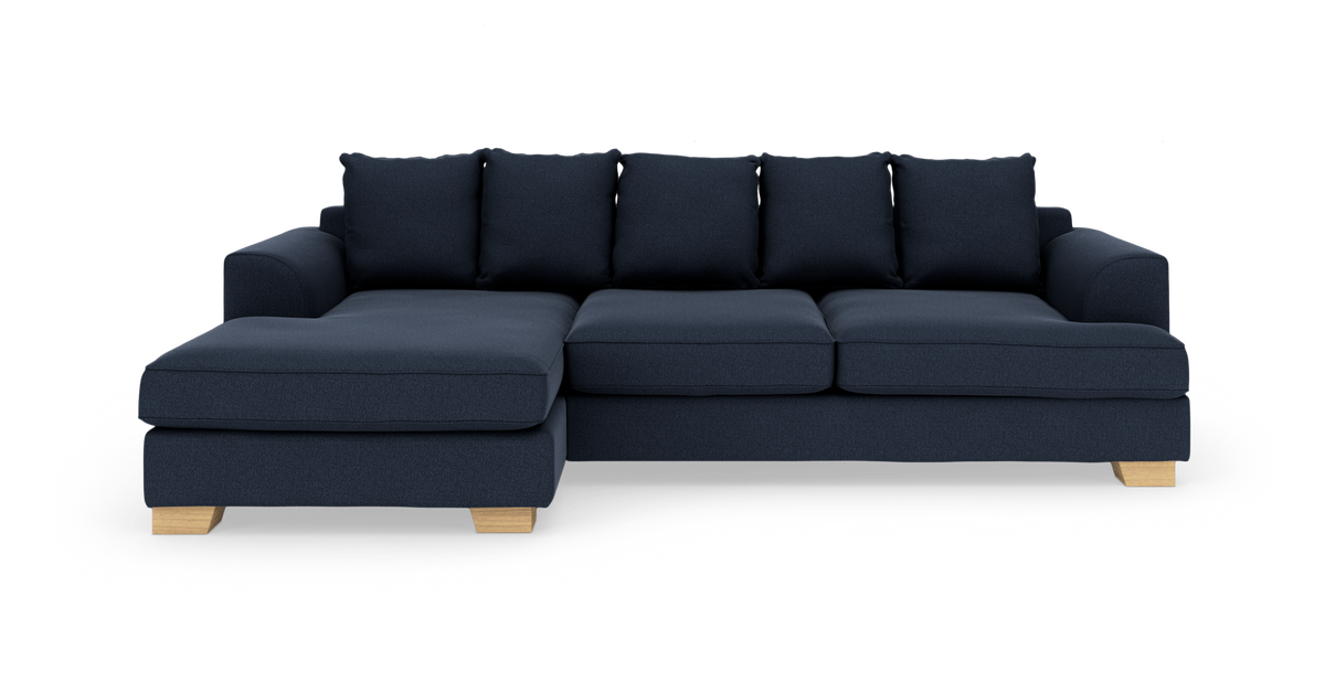 Mørkeblå hjørnesofa med venstre chaiselong, træben og løse ryghynder på hvid baggrund.
