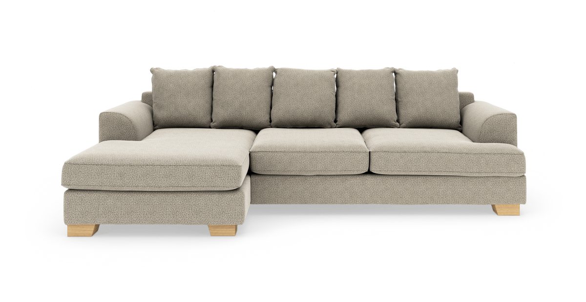 Beige hjørnesofa med venstrevendt chaiselong, fem rygpuder og lyse træben, frilagt på hvid baggrund.
