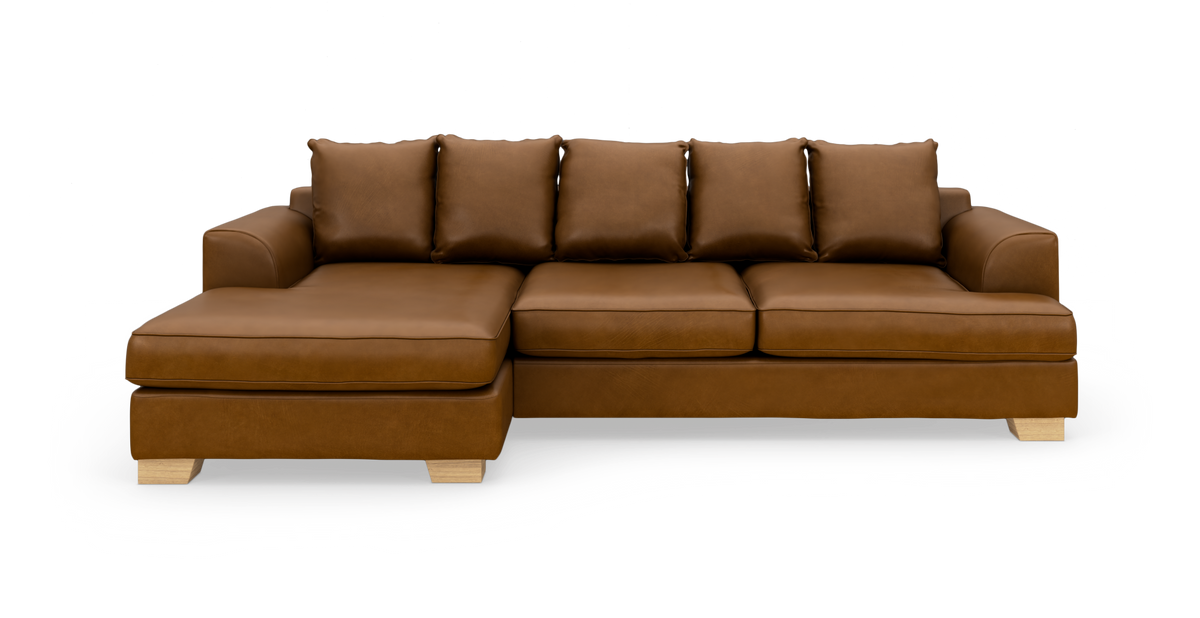 Brun lædersofa med venstrevendt chaiselong og fem løse rygpuder på lyse træben, fotograferet forfra mod hvid baggrund.