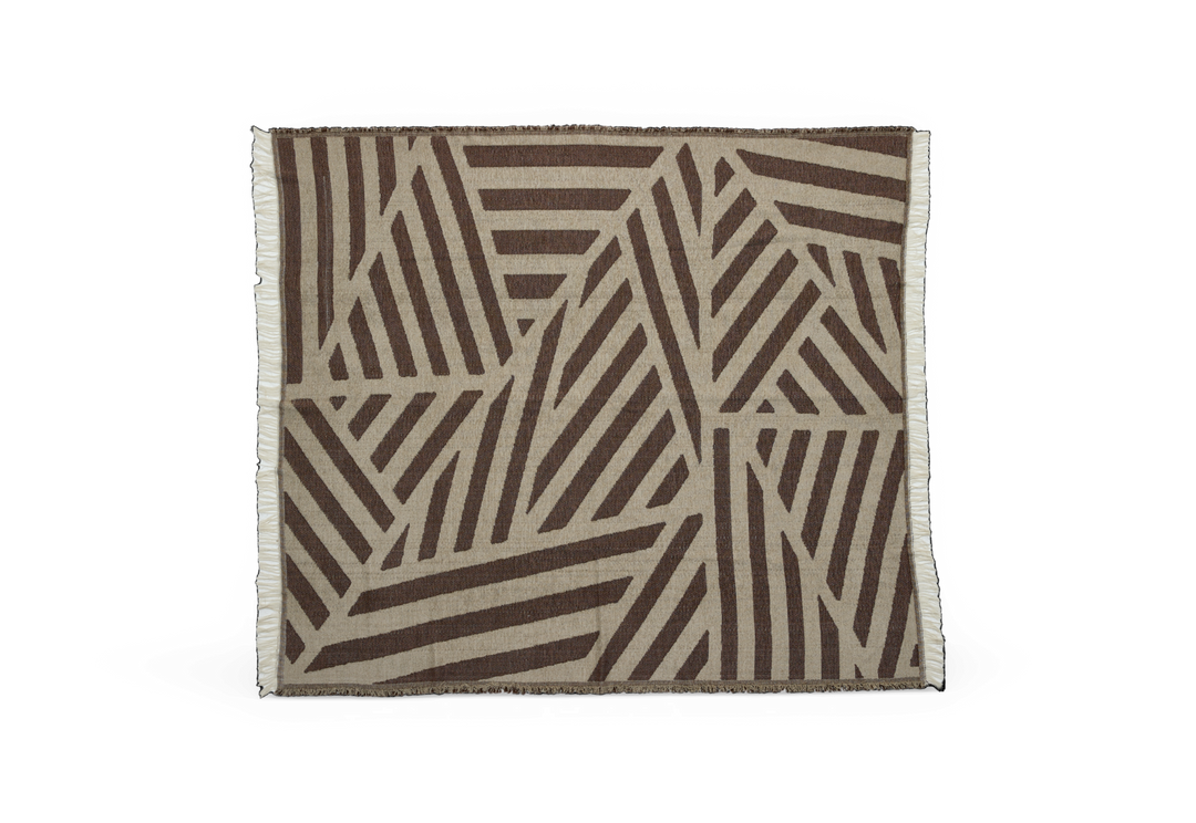 Beige tæppe med brune, grafiske striber og frynser i kanterne.
