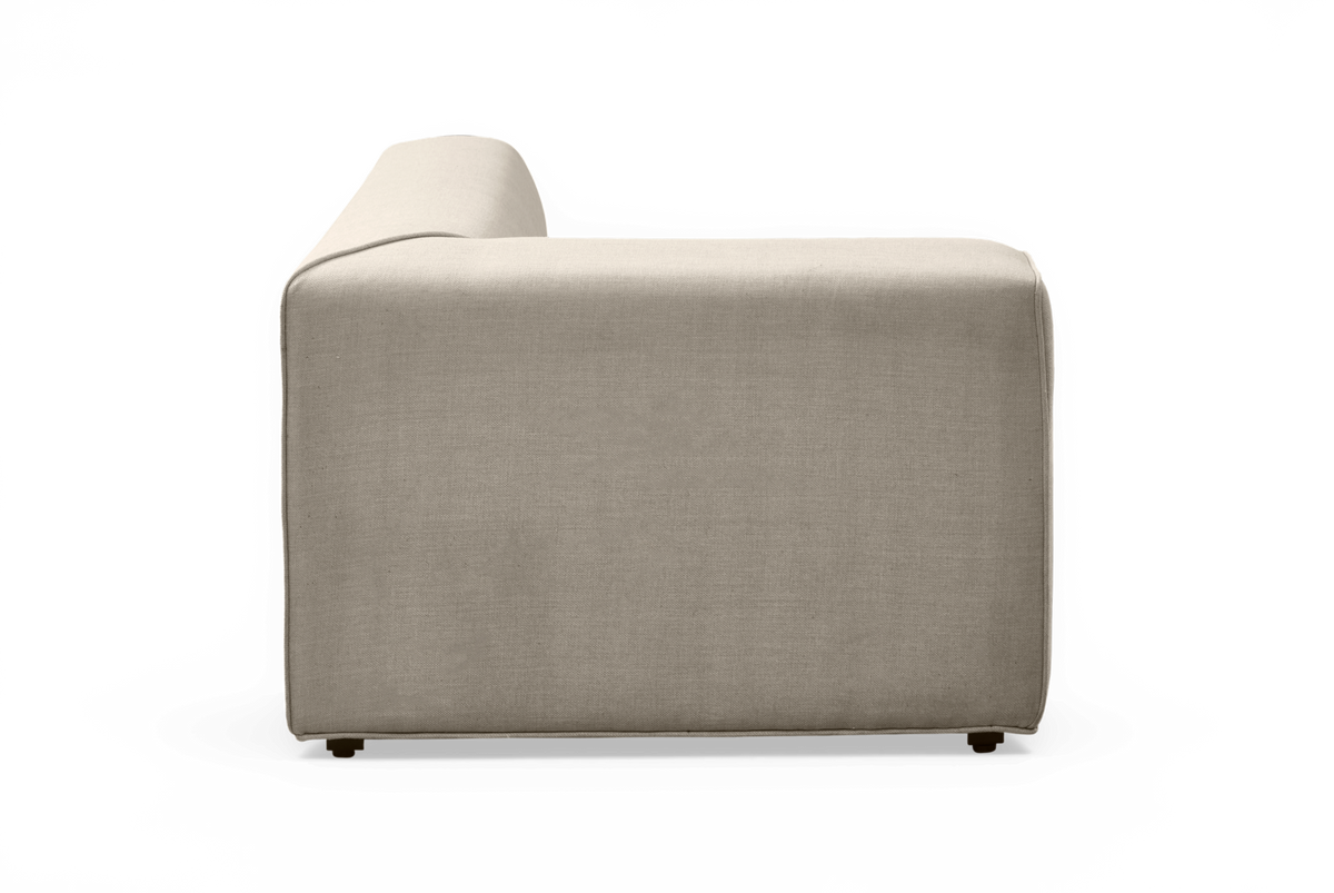 Sidevisning af beige modulsofa i stof med lav armlæn, frilagt på hvid baggrund.