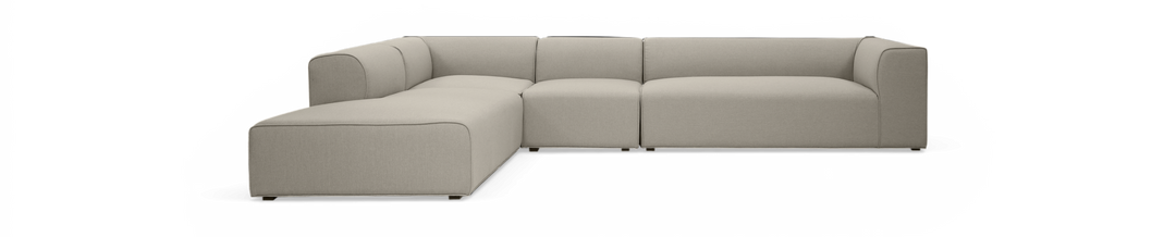 Modulær L‑formet beige stofsofa med chaiselong, fritlagt på sort baggrund.