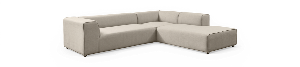 Modulær L‑formet beige stofsofa med højre chaiselong og lave, blokformede armlæn.