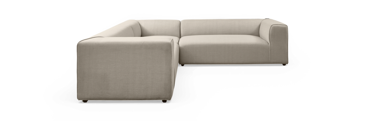 Beige L-formet modulsofa med bløde, afrundede kanter på sort baggrund.