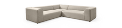 Beige L‑formet modulsofa i stof med brede armlæn, fritlagt på sort baggrund.