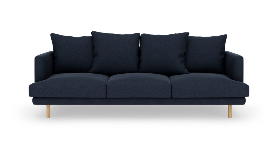 Mørkeblå tresæders sofa med fire store ryghynder og træben, fotograferet forfra på hvid baggrund.
