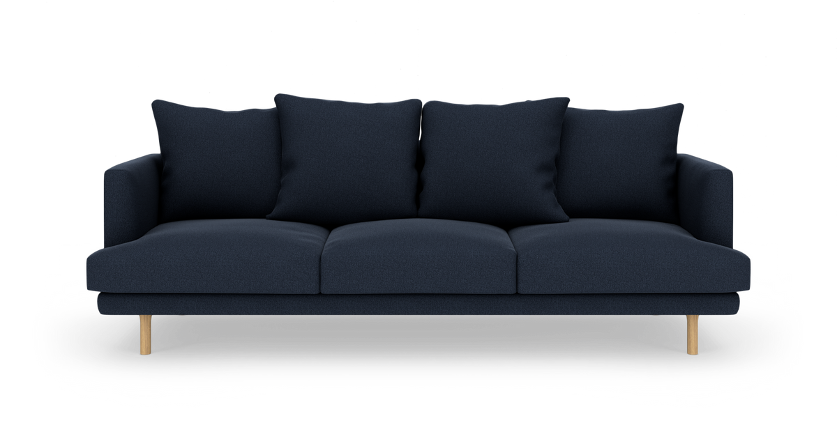 Mørkeblå tresæders sofa med fire store ryghynder og træben, fotograferet forfra på hvid baggrund.