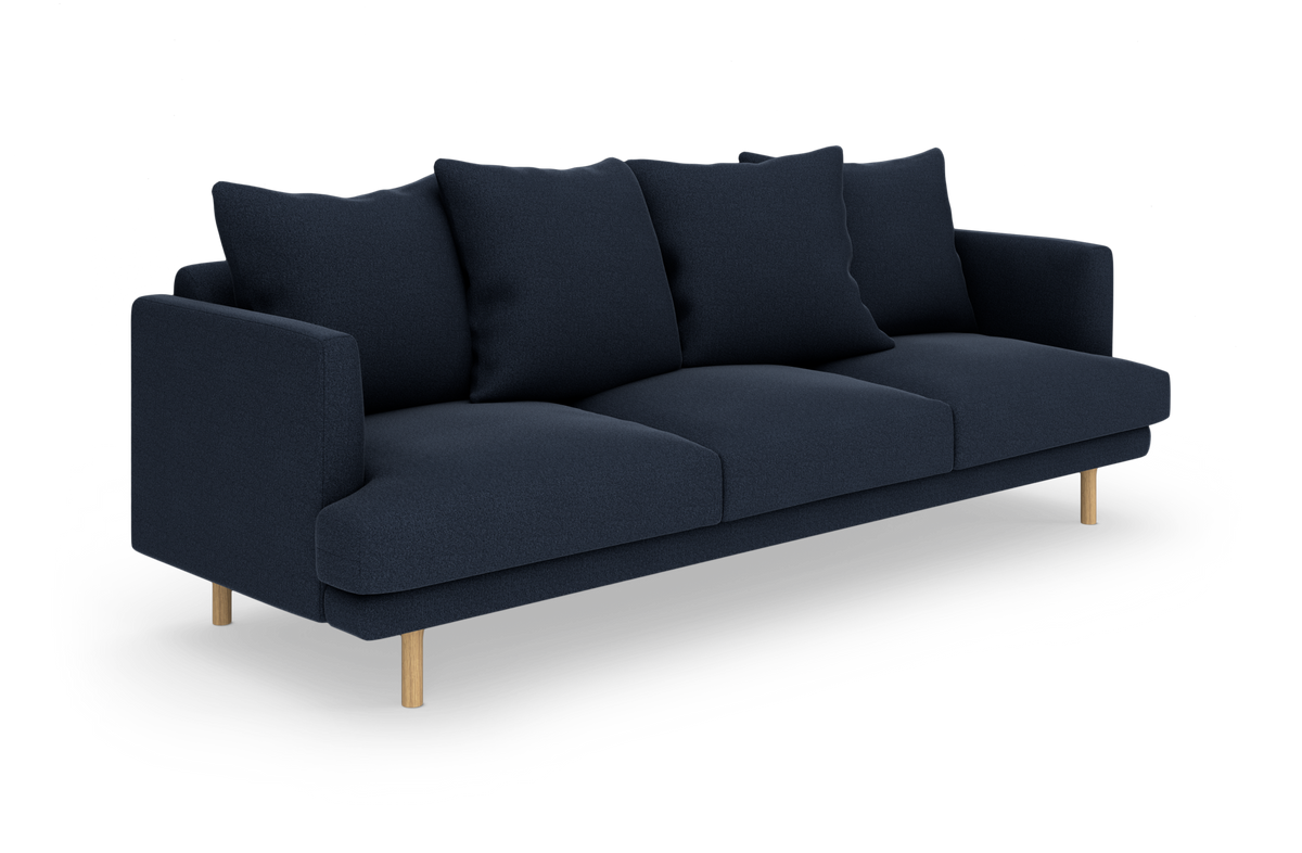 Mørkeblå tresædet sofa med fire rygpuder og lyse træben, frilagt på hvid baggrund.