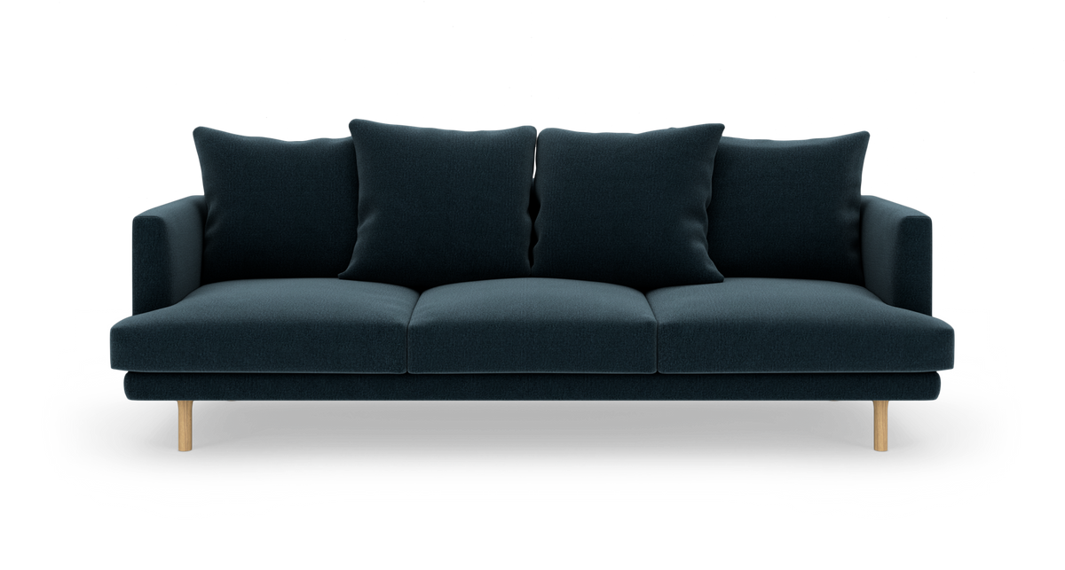Mørkeblå tresæders sofa med fire store ryghynder og lyse træben, set forfra.