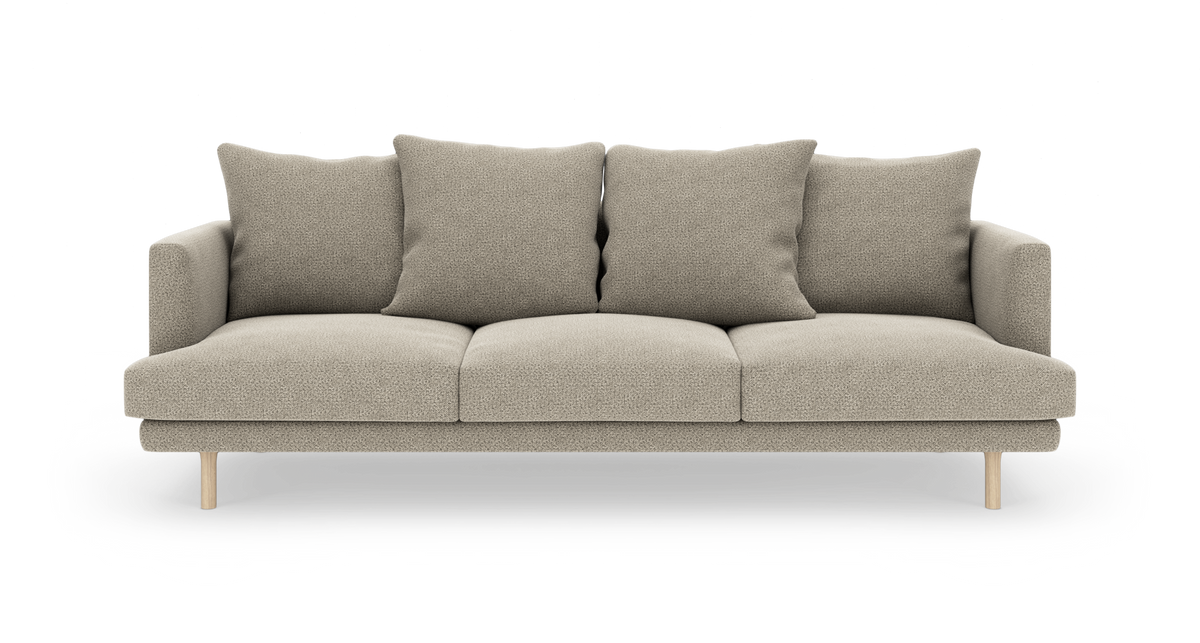 Beige 3-personers sofa med fire store ryghynder og lyse træben, frilagt på hvid baggrund.