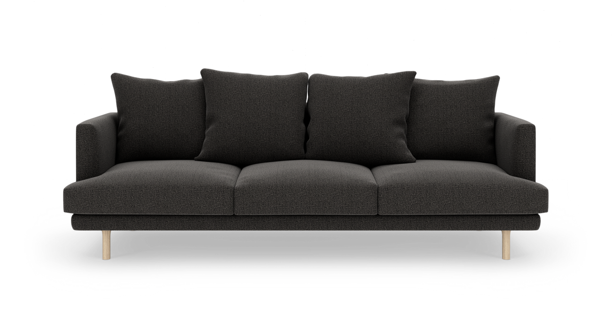 Mørkegrå tresæders sofa med fire rygpuder og lyse træben, frilagt på hvid baggrund.