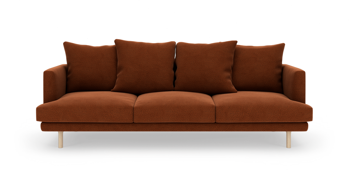 Rustbrun tresæders sofa i tekstil med fire løse ryghynder på lyse træben, frilagt på hvid baggrund.