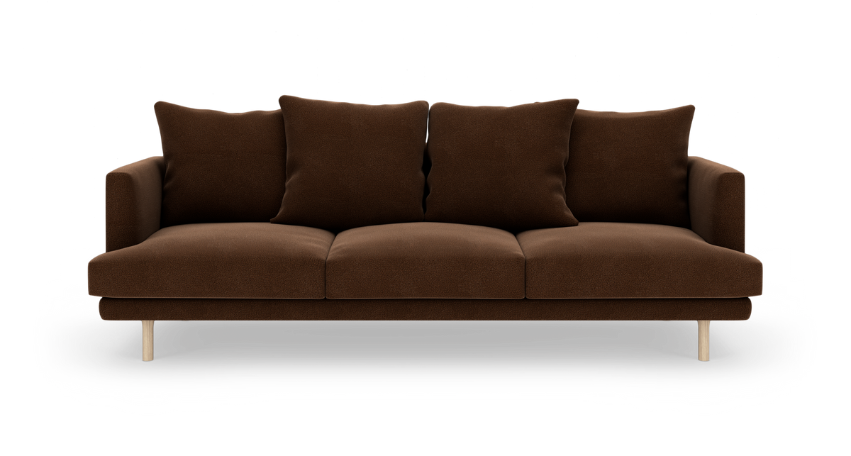 Brun 3-personers sofa med fire løse ryghynder og lyse træben, frilagt på hvid baggrund.