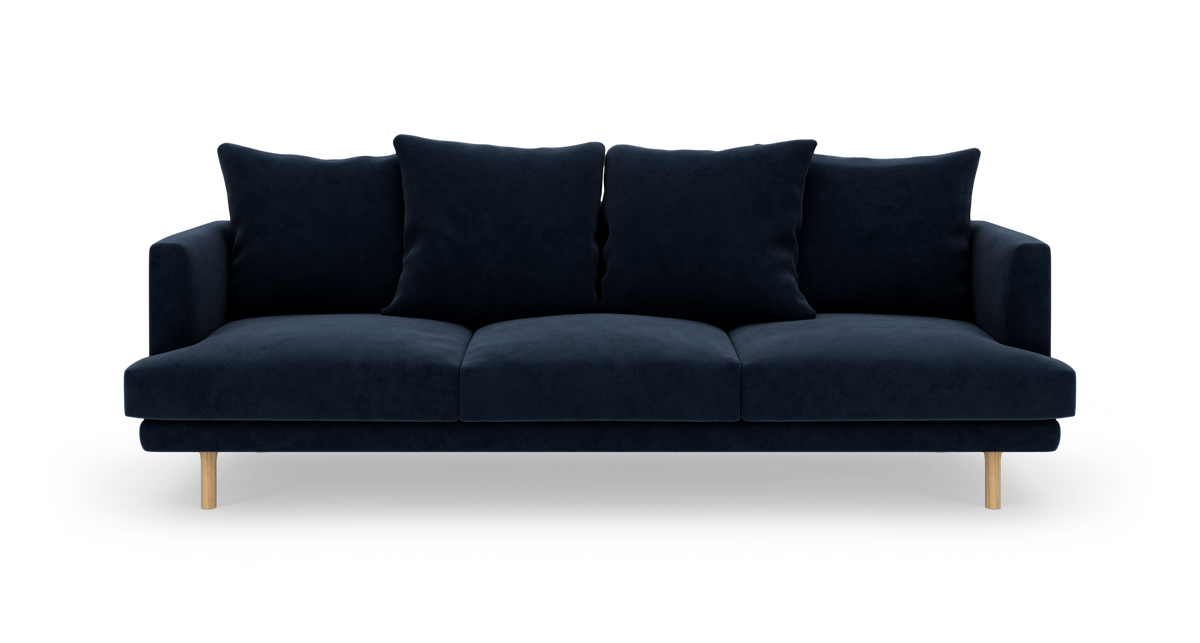 Mørkeblå tresæders sofa med fire store puder og lyse træben, fritlagt på hvid baggrund.