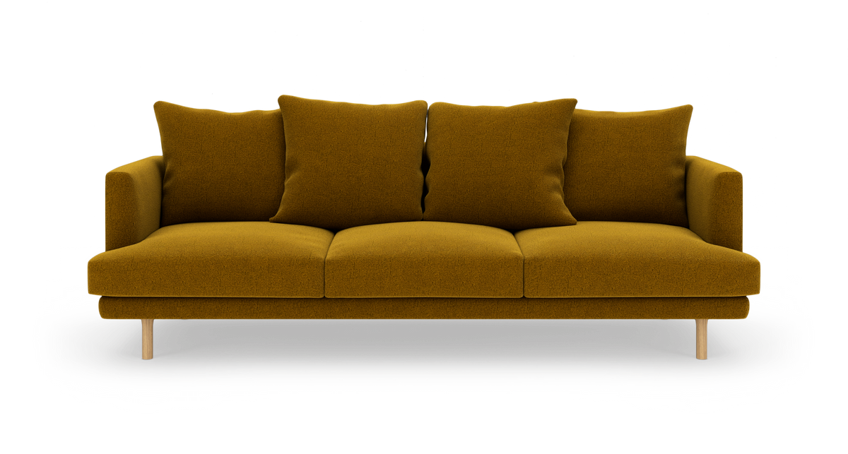 Sennepsgul tresæders sofa med fire puder og træben, frontvisning på hvid baggrund.