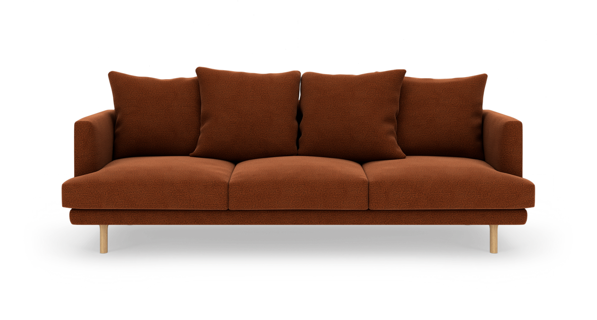 Brun 3-personers sofa med fire løse ryghynder og lyse træben, fotograferet lige forfra på hvid studiobaggrund.