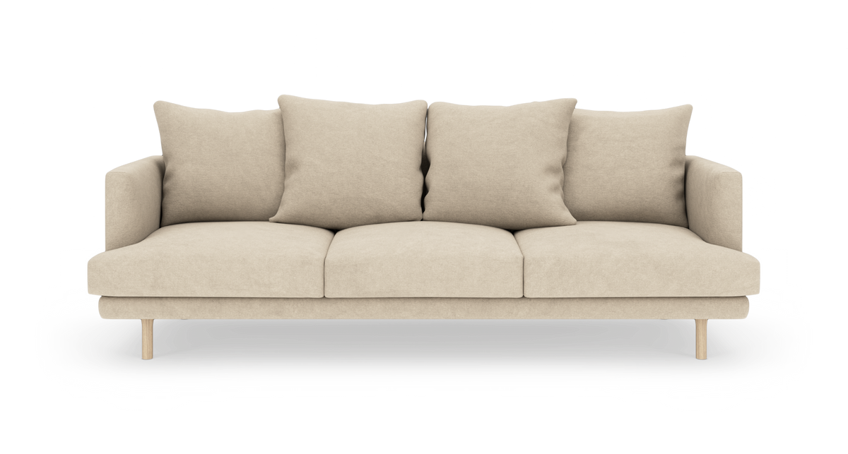 Beige 3-personers sofa med fire løse ryghynder og træben, frilagt på hvid baggrund.