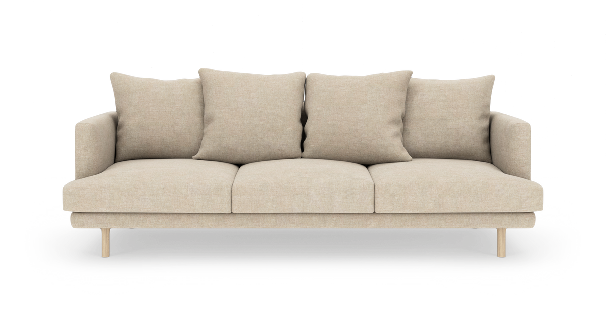 Beige 3-personers sofa med løse ryndekuder og slanke træben, set lige forfra i studiemiljø.