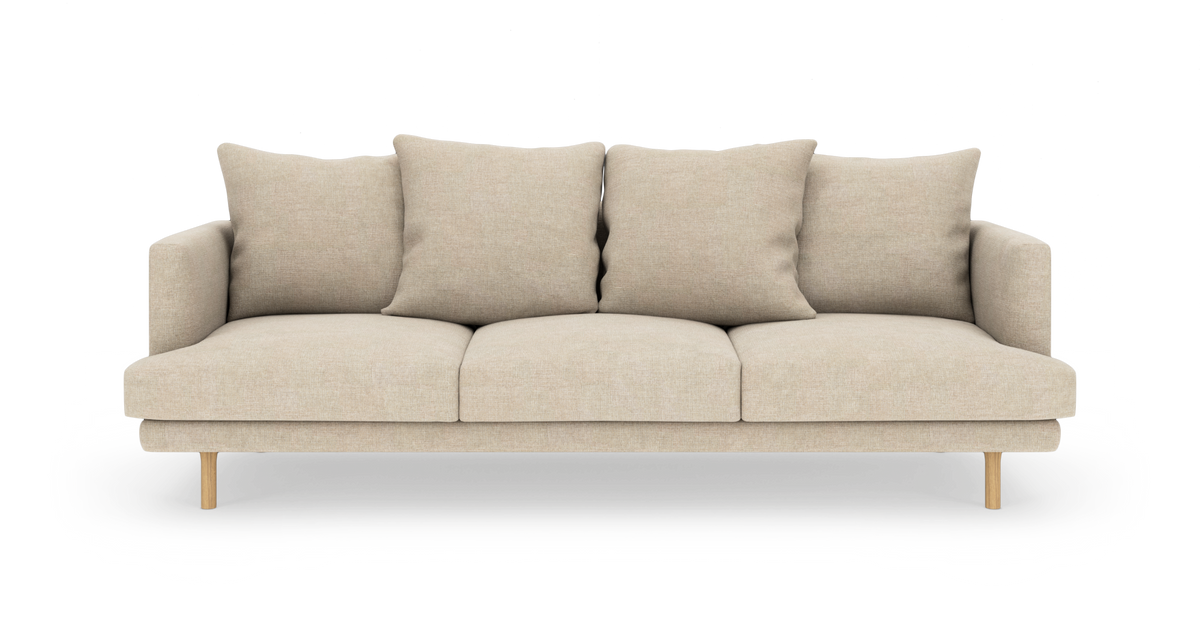 Beige 3-personers sofa med fire rygpuder og træben, frilagt på hvid baggrund.