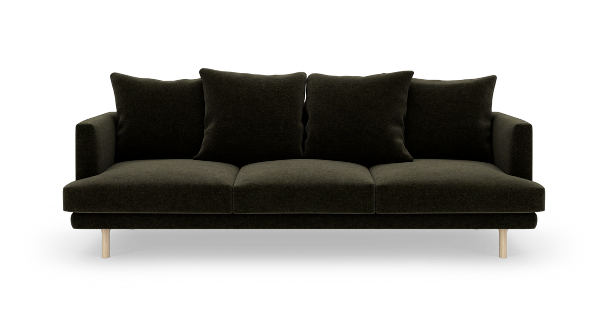 Mørkegrøn tresæders sofa med fire løse ryghynder og lyse træben, frilagt mod hvid baggrund.