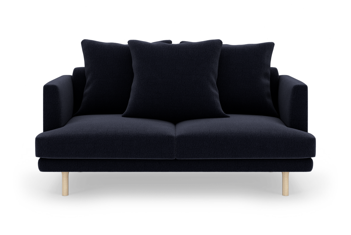 Mørkeblå 2-personers sofa med tre store puder og lyse træben, frilagt mod hvid baggrund.