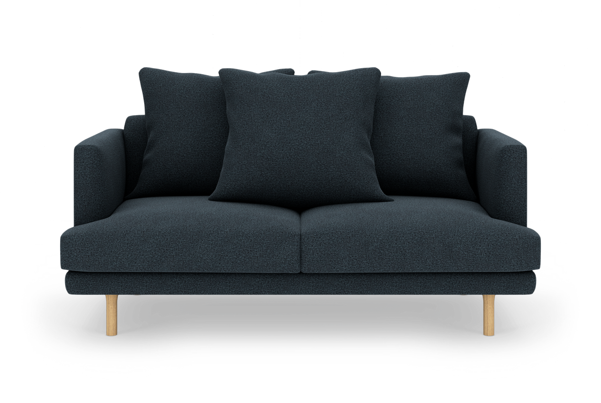 Mørkeblå 2-personers sofa med tre store puder og lyse træben, frilagt mod hvid baggrund.
