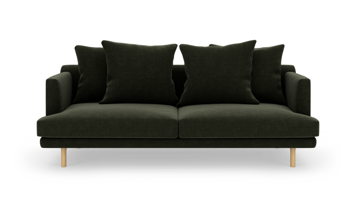 Mørkegrøn sofa med fire store puder og lyse træben, frilagt på hvid baggrund.