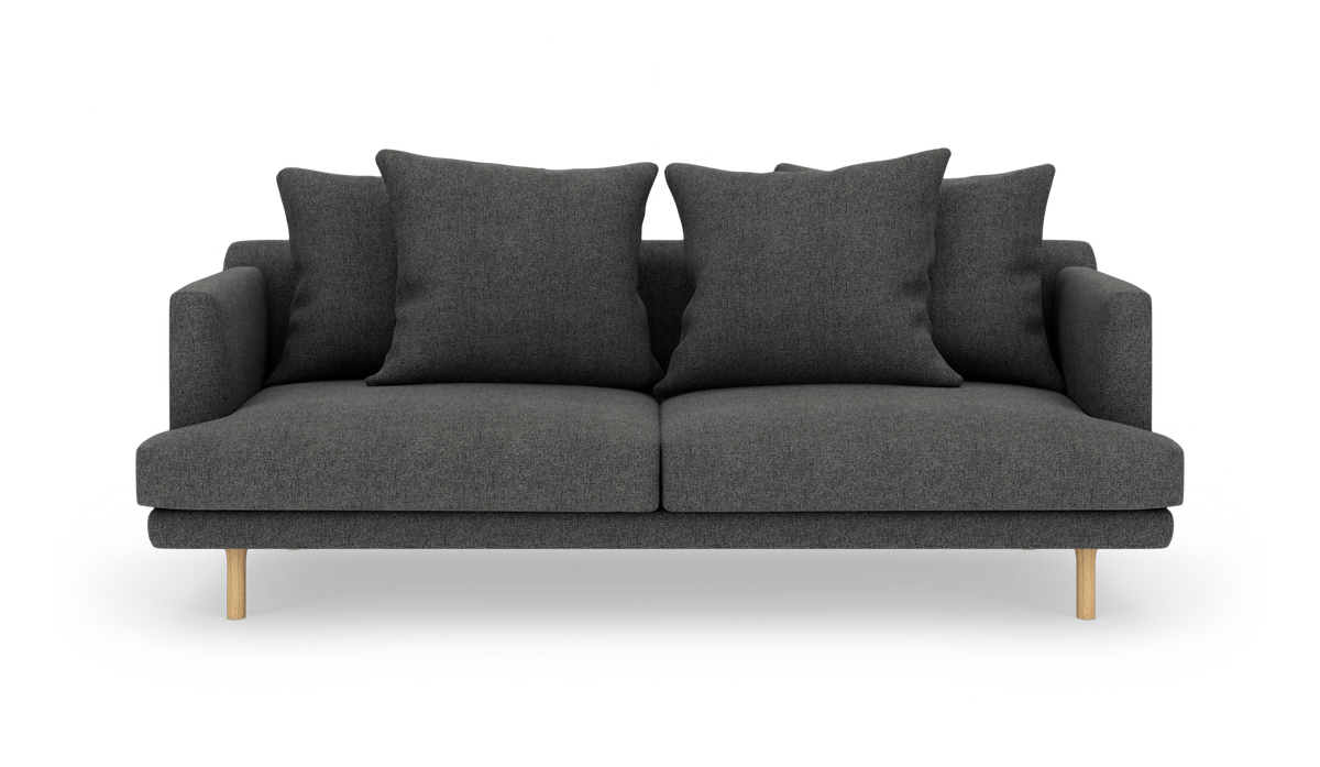 Mørkegrå sofa med fire store puder og lyse træben, fotograferet forfra.