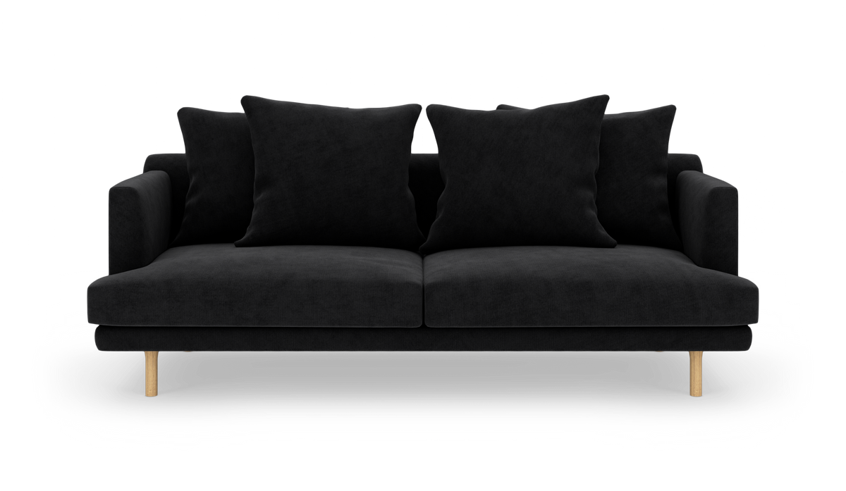 Sort sofa med fire store puder og lyse træben, frilagt på hvid baggrund.
