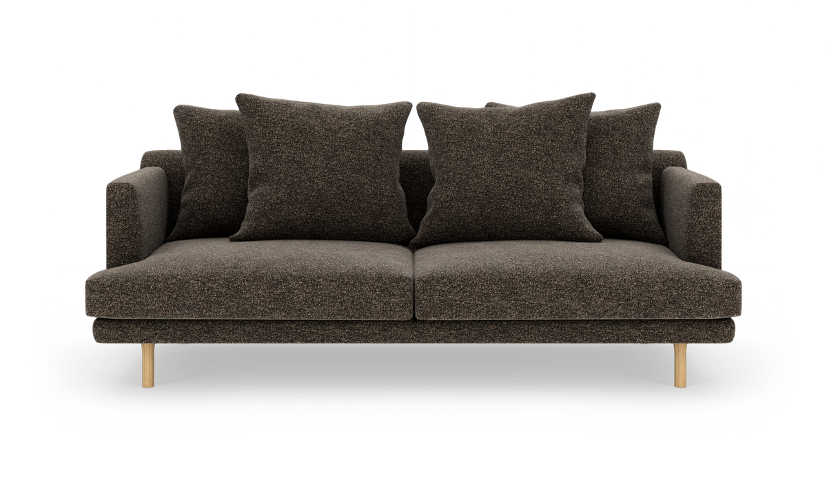 Mørkebrun sofa med fire store puder og træben, frilagt på hvid baggrund.