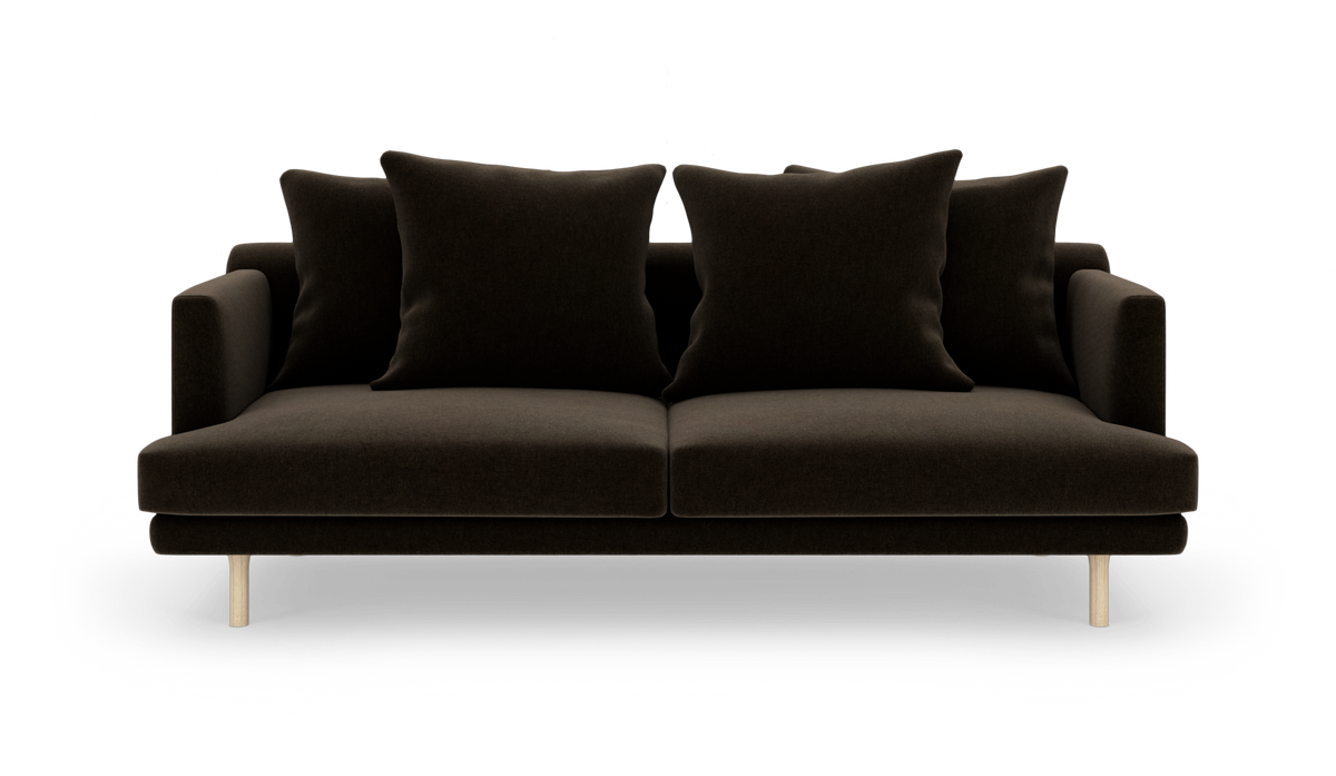 Mørkebrun sofa med fire store puder og lyse træben, set forfra.