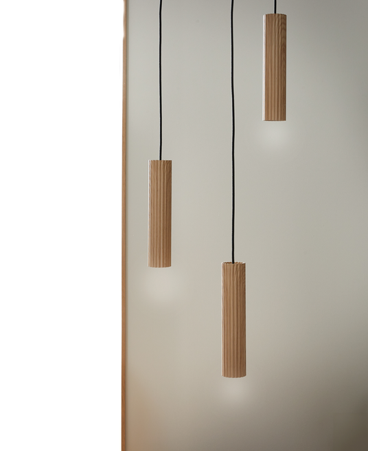 Tre hængende cylindriske pendellamper i lyst træ med sorte ledninger mod lys, neutral baggrund.