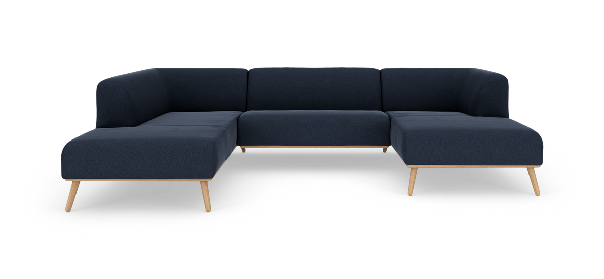 Mørkeblå modul-hjørnesofa i L‑form med træramme og skrå træben, frilagt på hvid baggrund.