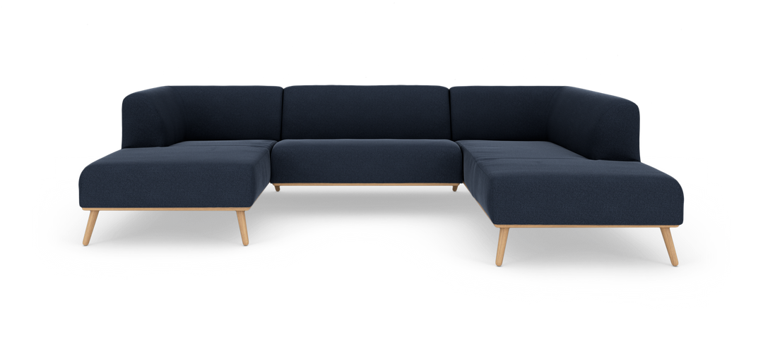 Mørkeblå modulsofa i U‑form med træben, frilagt på hvid baggrund.