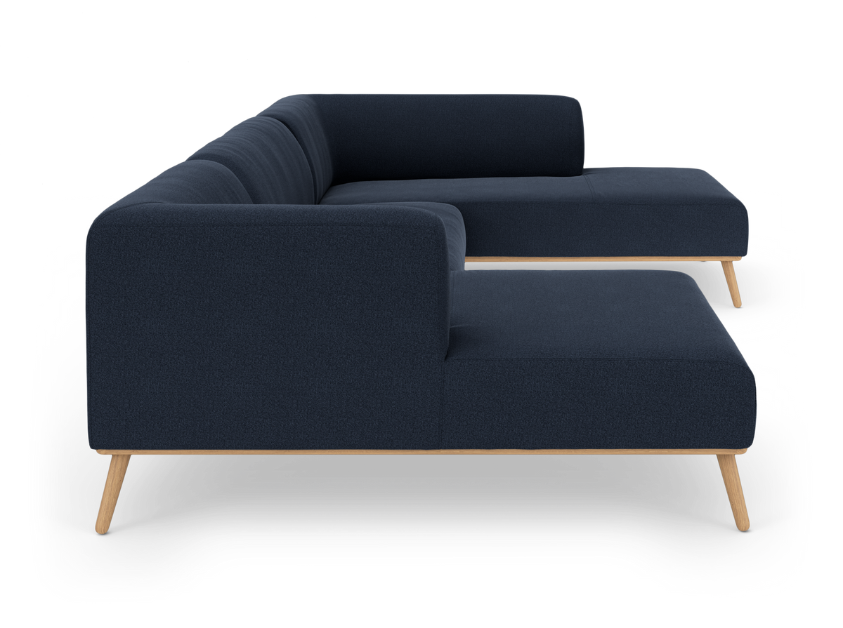 Mørkeblå modulsofa med træramme og skråtstillede ben, set fra siden på hvid baggrund.