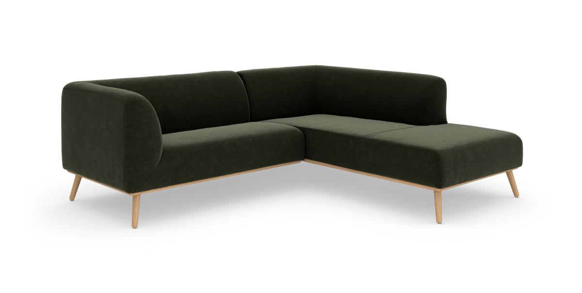 Mørkegrøn hjørnesofa med afrundede kanter og slanke træben, frilagt på hvid baggrund.