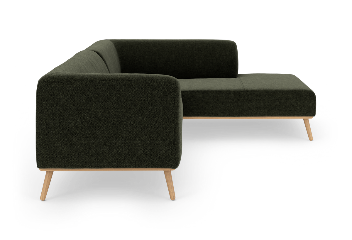Mørkegrøn L-formet sofa med træben på hvid studiobaggrund.