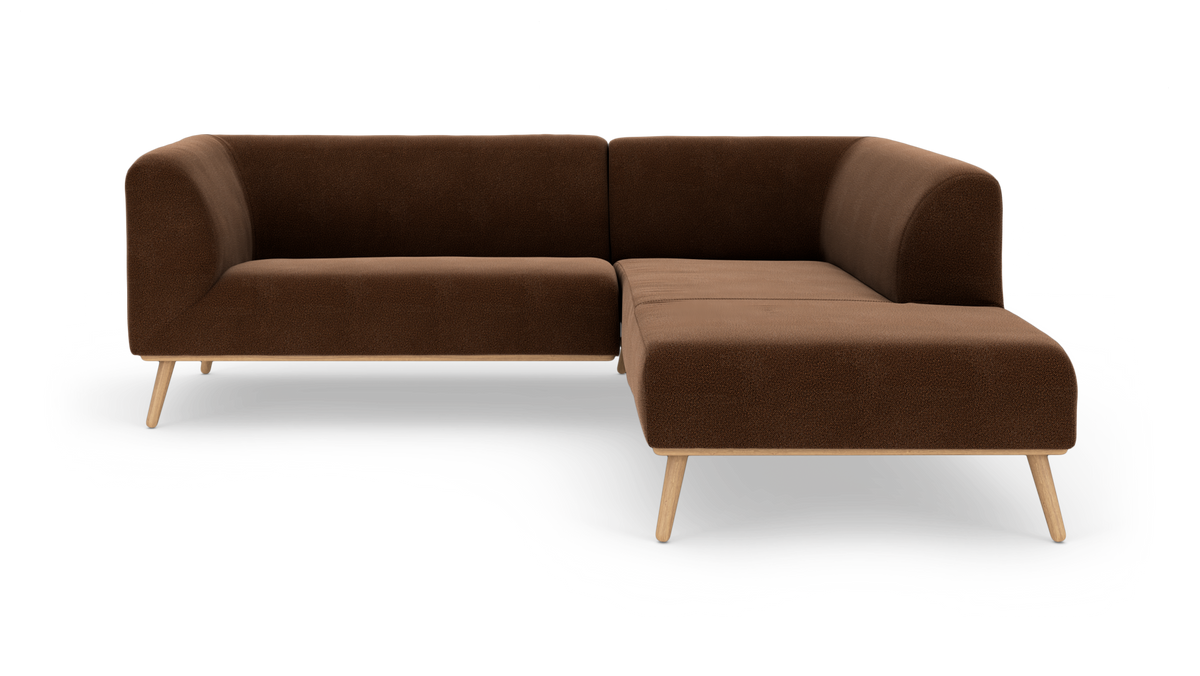 Brun L-formet hjørnesofa med træben i studiomiljø, set forfra.