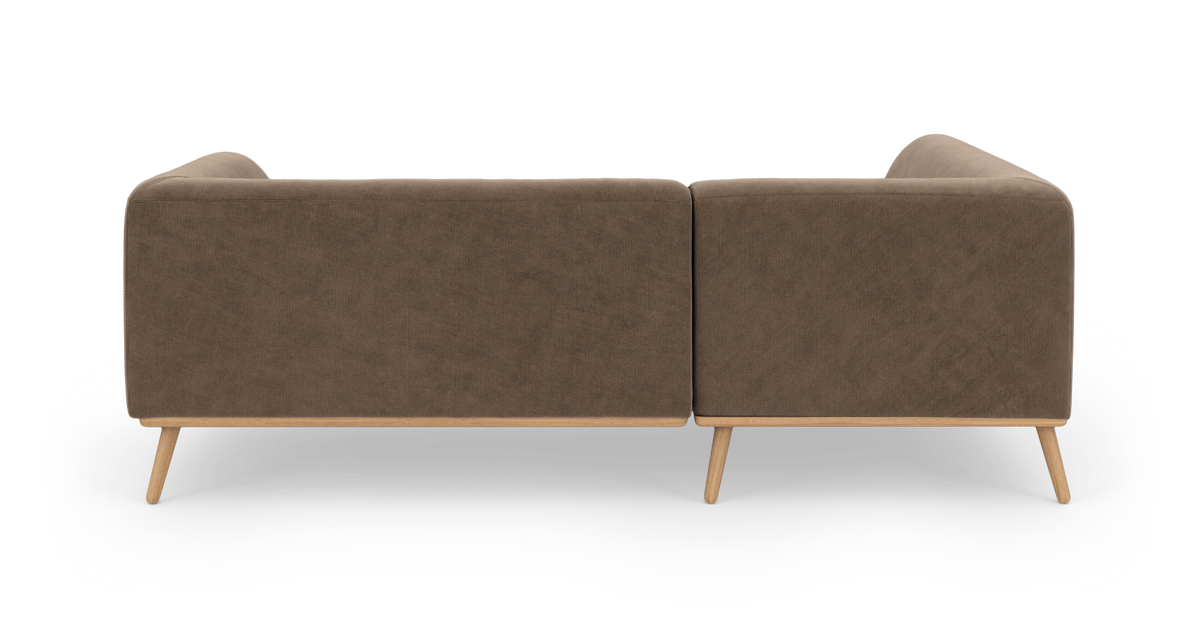 Brun modulsofa i fløjl med lyse træben set bagfra, frilagt på hvid baggrund.