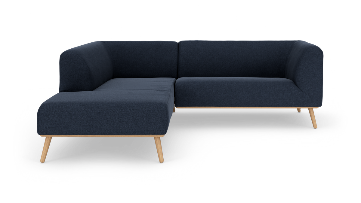 Mørkeblå hjørnesofa med venstrevendt chaiselong og træben på hvid baggrund.