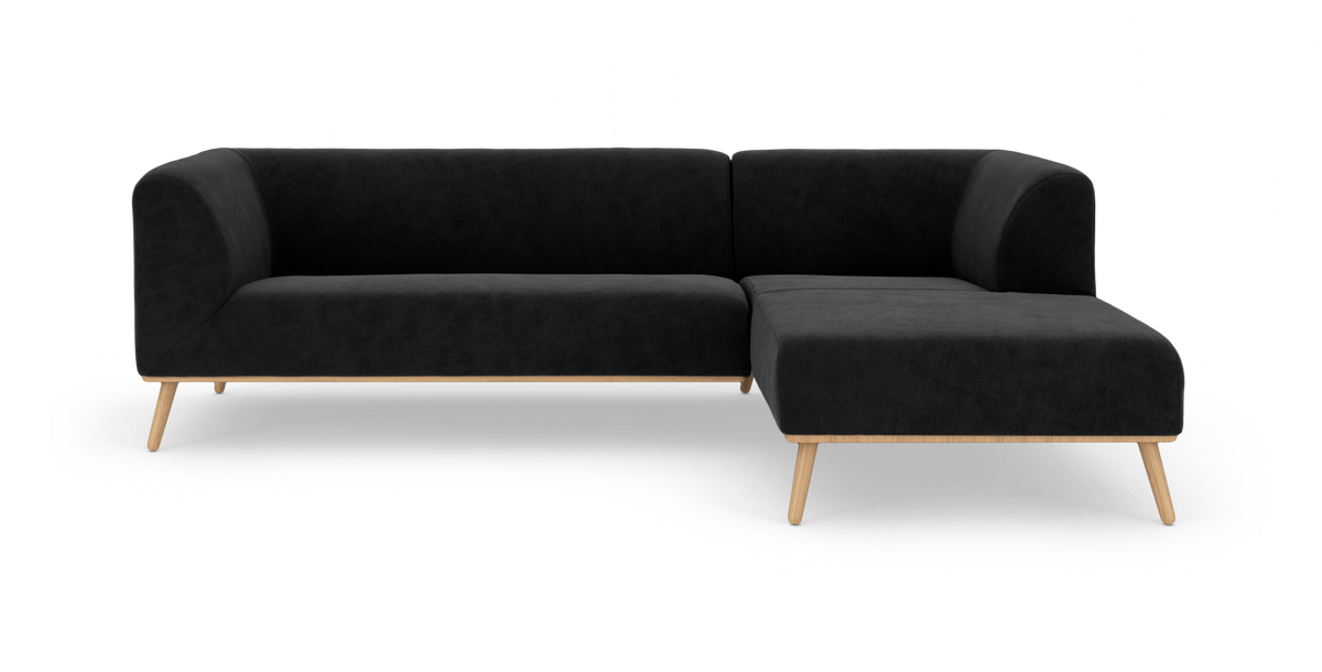 Sort L‑sofa med chaiselong til højre og lyse træben på hvid studiobaggrund.