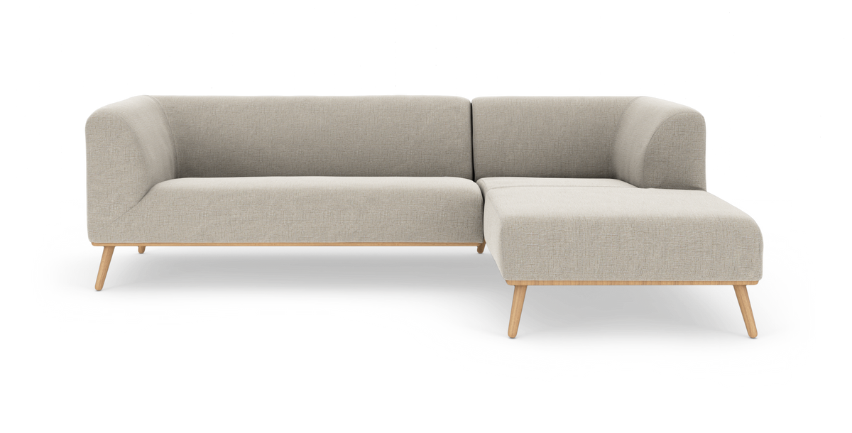 L‑formet modulsofa i lys beige stof med træben, frilagt på hvid baggrund.