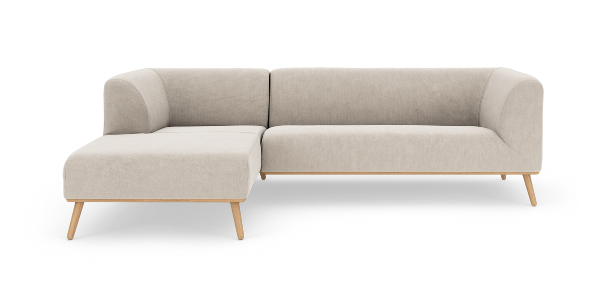 Lys beige modulsofa med venstre chaiselong på træben, fritlagt mod hvid baggrund.