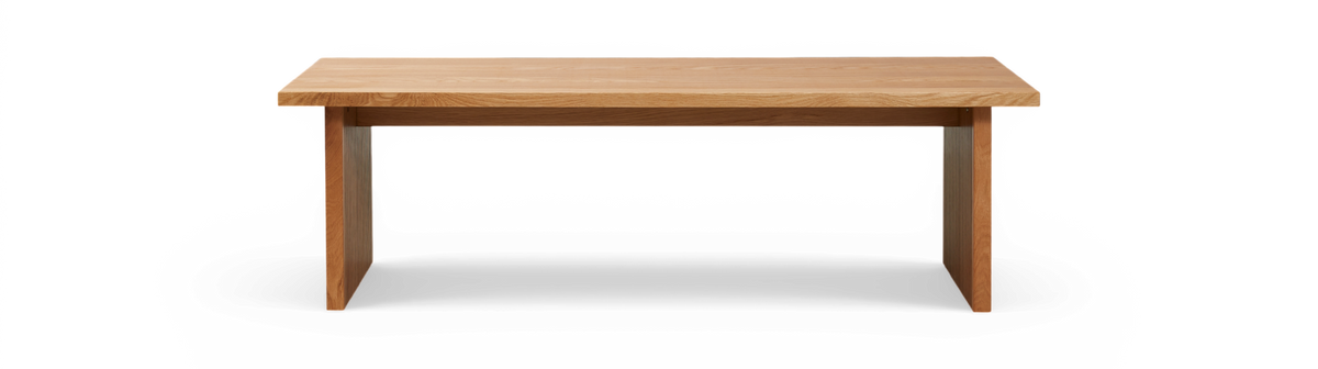 Rektangulær bænk i massiv eg med riflede ben, frilagt mod sort baggrund, set forfra.