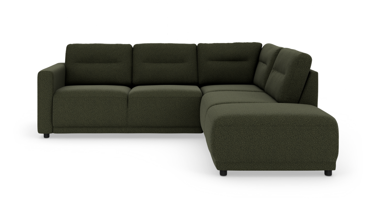 Mørkegrøn L-formet hjørnesofa med chaiselong til højre, bløde kraftige hynder og korte sorte ben i studielys.