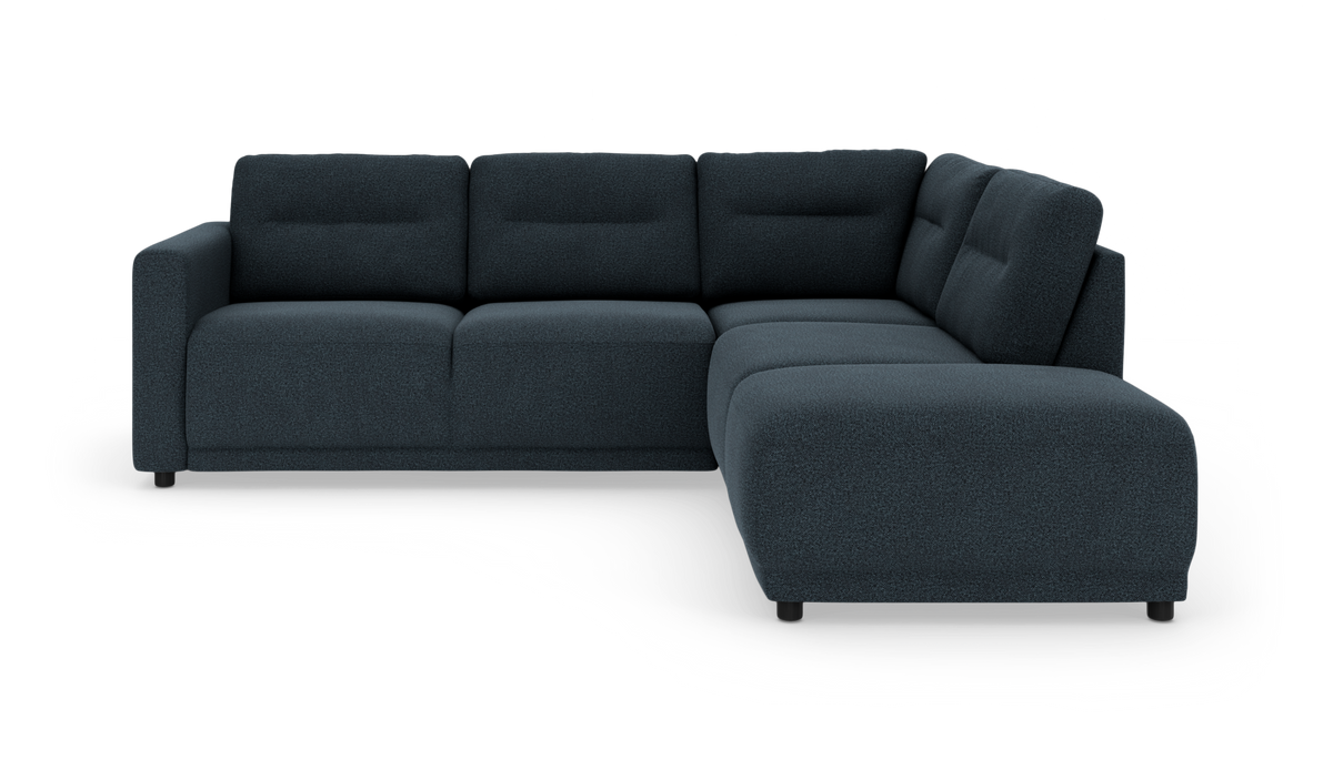 Mørkeblå L‑sofa med chaiselong til højre, bløde ryghynder og korte sorte ben, frilagt på hvid baggrund.