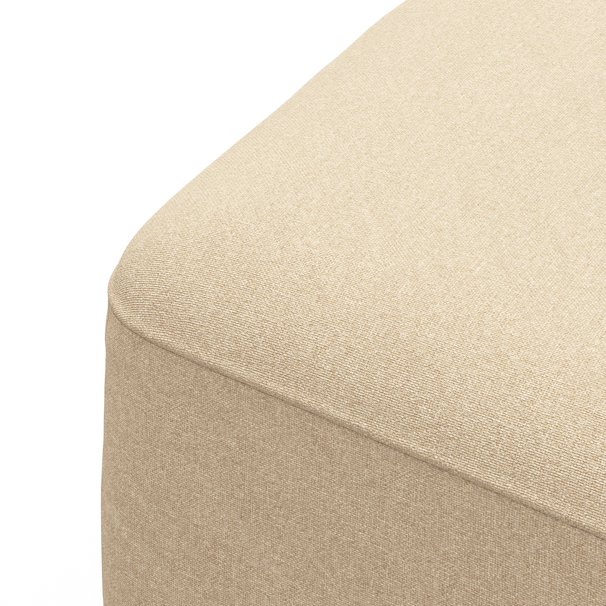 Nærbillede af en beige stofpuf/ottoman med afrundet hjørne mod hvid baggrund.