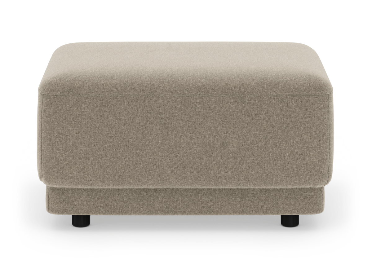 Beige firkantet stofpuf/ottoman med lave sorte ben, frilagt på hvid baggrund.