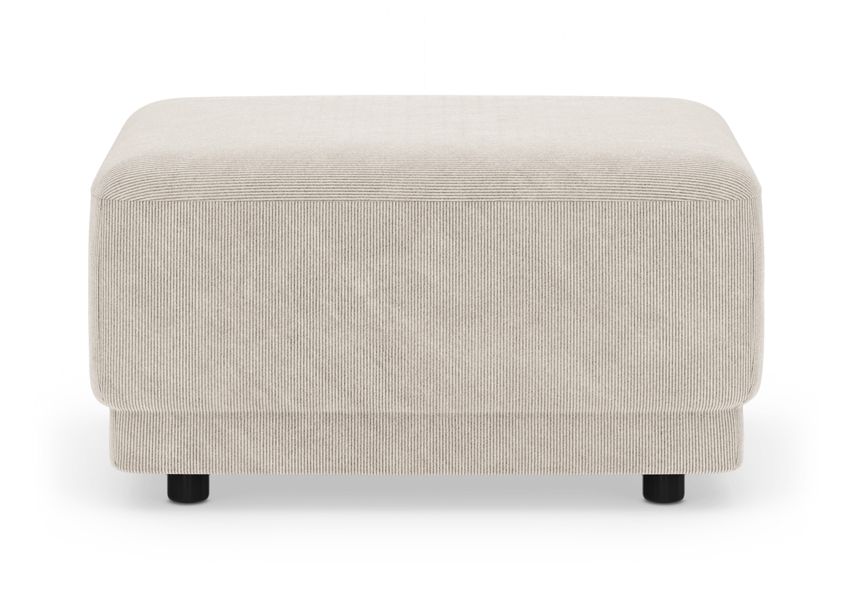 Beige puf i bredriflet fløjl med runde sorte ben, fritlagt på hvid baggrund.