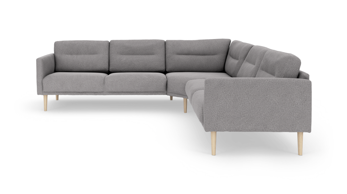 L-formet grå hjørnesofa med slanke træben, frilagt på hvid baggrund.